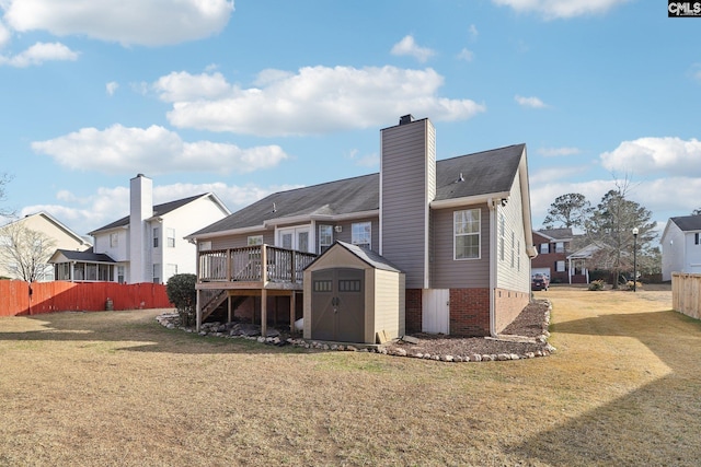 back of property featuring a yard, a deck, and a storage shed