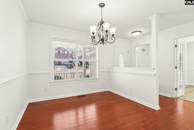 unfurnished dining area featuring ornamental molding, wood-type flooring, and a notable chandelier