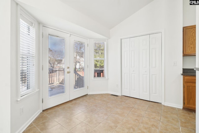 interior space with light tile patterned floors, vaulted ceiling, and french doors