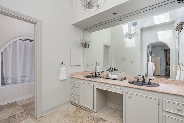 bathroom featuring an inviting chandelier, vanity, and tiled bath