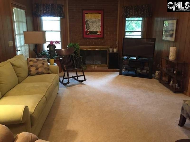 carpeted living room with a brick fireplace and wood walls