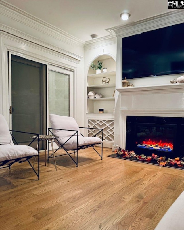 sitting room with crown molding, light hardwood / wood-style floors, and built in shelves