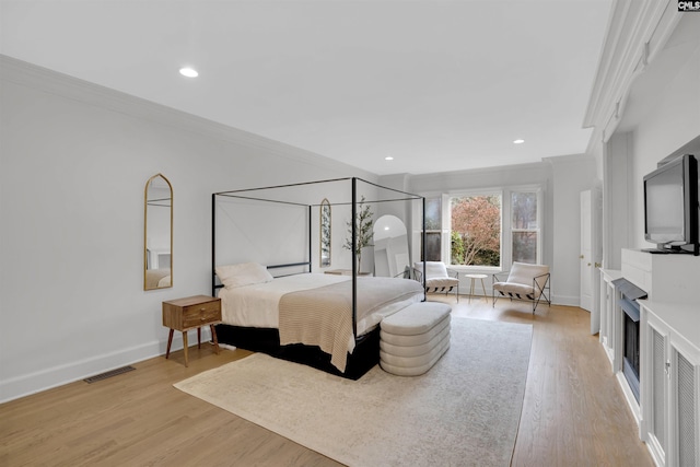 bedroom featuring ornamental molding and light hardwood / wood-style flooring