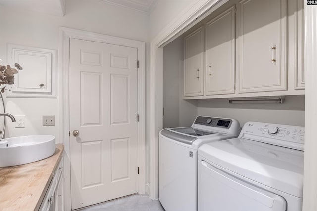 laundry room featuring sink, crown molding, washing machine and dryer, and cabinets