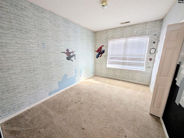 unfurnished room featuring light carpet, a textured ceiling, and brick wall