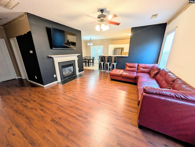 living room featuring ceiling fan, hardwood / wood-style floors, and a textured ceiling