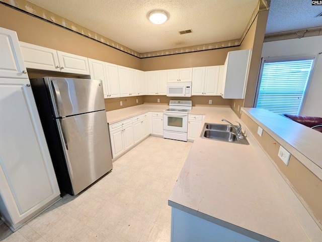 kitchen featuring sink, white appliances, white cabinetry, a textured ceiling, and kitchen peninsula