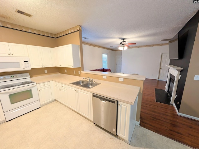 kitchen with white appliances, kitchen peninsula, sink, and white cabinets