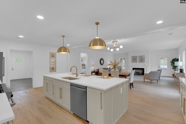 kitchen featuring pendant lighting, sink, a kitchen island with sink, stainless steel appliances, and light wood-type flooring