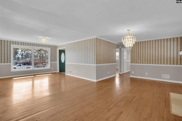 unfurnished living room with crown molding, a notable chandelier, and hardwood / wood-style flooring