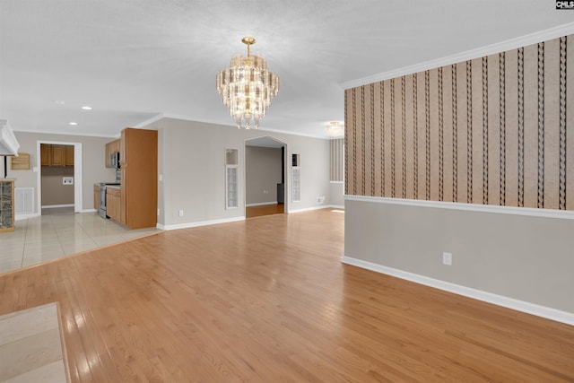 unfurnished living room with a notable chandelier, ornamental molding, and light wood-type flooring