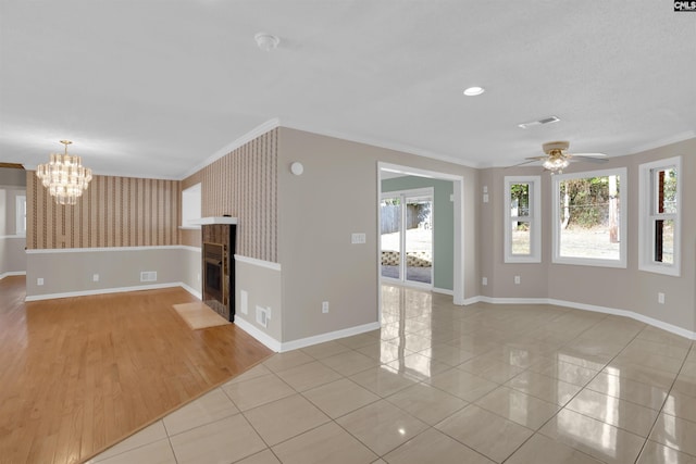 unfurnished living room featuring light tile patterned floors, ceiling fan with notable chandelier, and ornamental molding