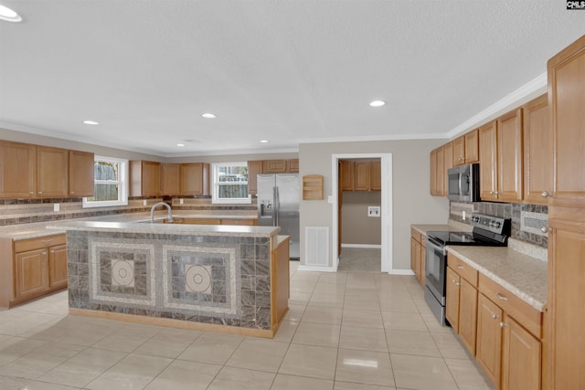 kitchen with sink, light tile patterned floors, an island with sink, stainless steel appliances, and decorative backsplash