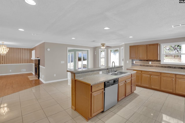 kitchen with sink, a brick fireplace, light tile patterned floors, dishwasher, and an island with sink