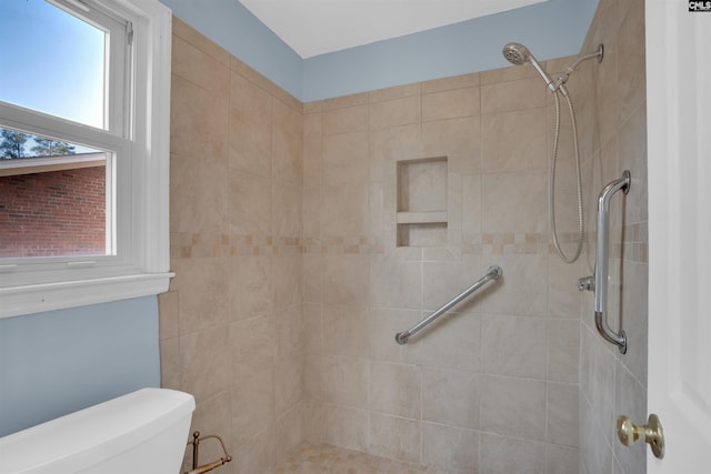 bathroom featuring plenty of natural light, toilet, and a tile shower