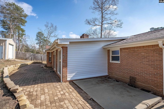 view of side of property with a patio and an outbuilding