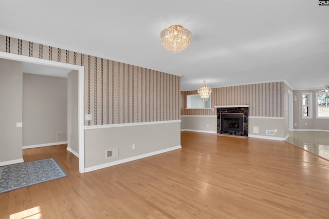 unfurnished living room featuring ceiling fan with notable chandelier and light hardwood / wood-style floors