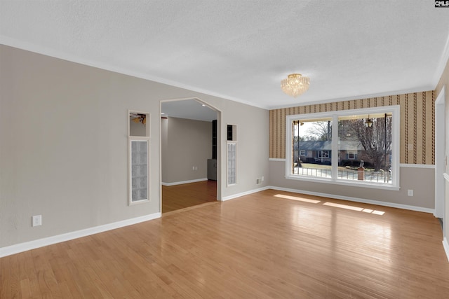 unfurnished room with ornamental molding, a textured ceiling, and light hardwood / wood-style flooring