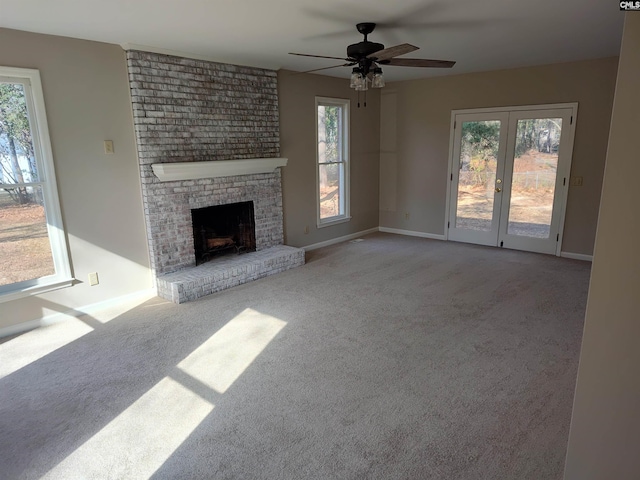 unfurnished living room featuring light carpet, a fireplace, french doors, and ceiling fan