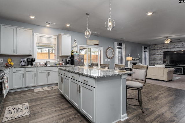 kitchen with white cabinetry, a kitchen island, decorative light fixtures, and light stone counters