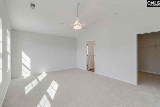 unfurnished bedroom featuring a walk in closet, light colored carpet, high vaulted ceiling, and a closet