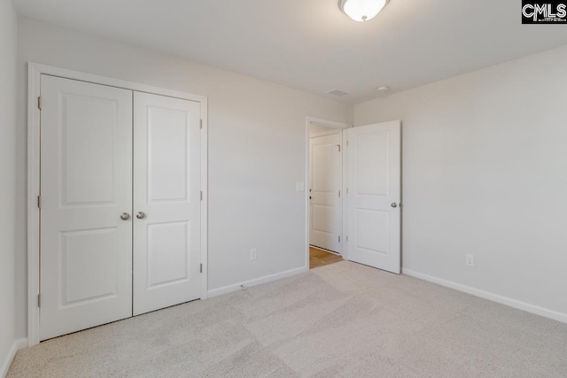 unfurnished bedroom with a closet and light carpet