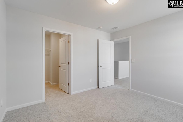 unfurnished bedroom with a walk in closet and light colored carpet