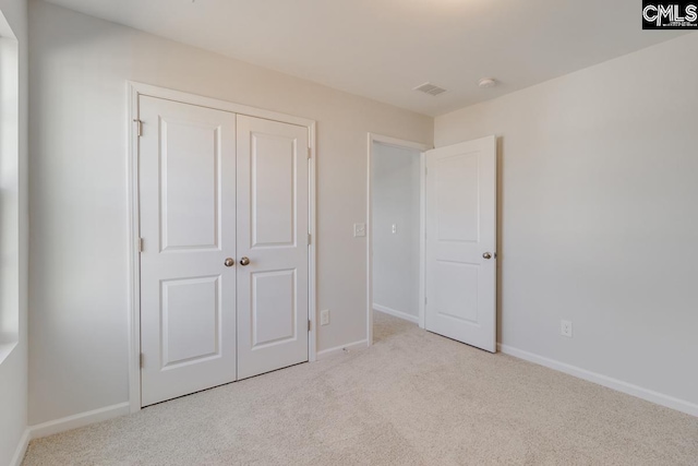 unfurnished bedroom featuring light colored carpet and a closet