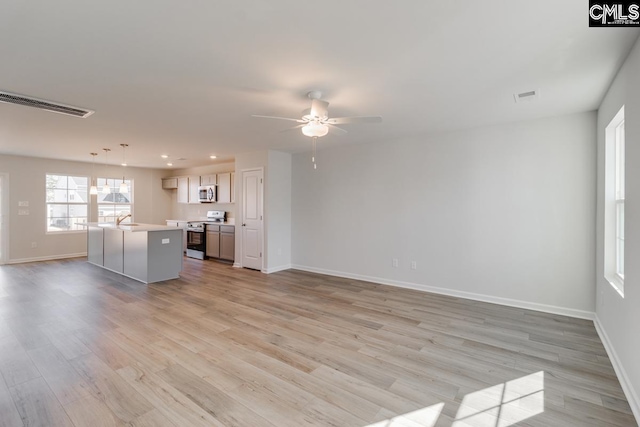 unfurnished living room featuring ceiling fan, sink, and light hardwood / wood-style floors