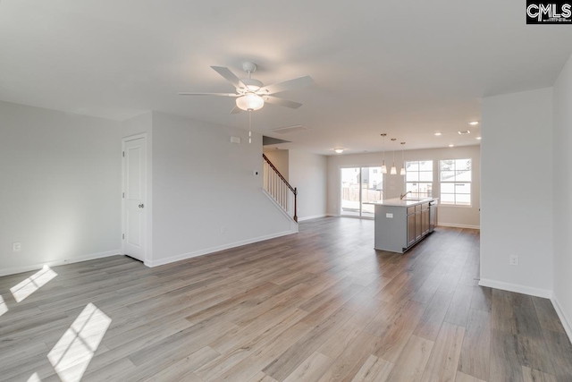 unfurnished living room featuring sink, light hardwood / wood-style floors, and ceiling fan