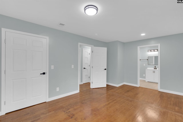 unfurnished bedroom featuring hardwood / wood-style flooring and ensuite bath