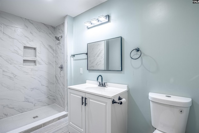 bathroom with vanity, toilet, and a tile shower