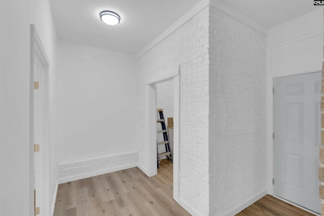 hall featuring brick wall and light wood-type flooring