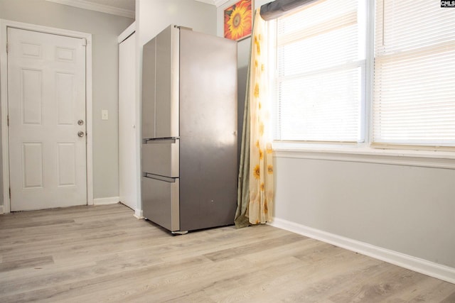 kitchen featuring a wealth of natural light, freestanding refrigerator, crown molding, and light wood-style floors