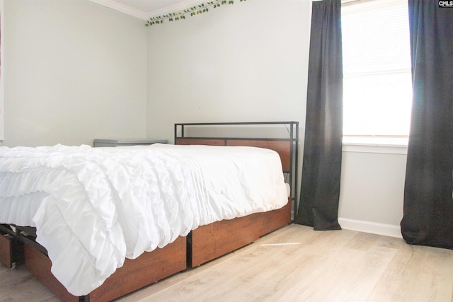 bedroom with crown molding, baseboards, and light wood-style floors