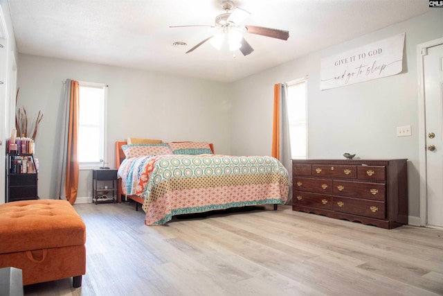 bedroom featuring light wood-style floors, visible vents, ceiling fan, and baseboards