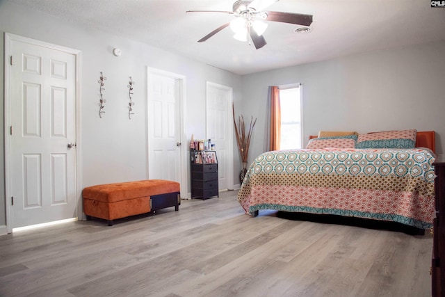 bedroom featuring light wood-style floors, visible vents, ceiling fan, and baseboards