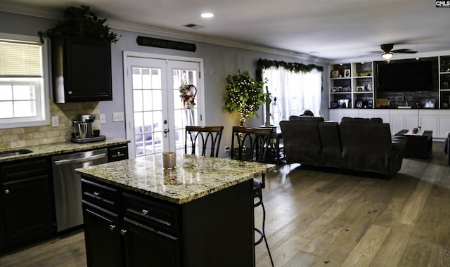 kitchen with hardwood / wood-style flooring, dishwasher, a center island, light stone counters, and french doors