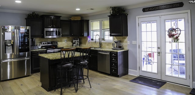 kitchen with sink, stainless steel appliances, light stone countertops, a kitchen island, and french doors