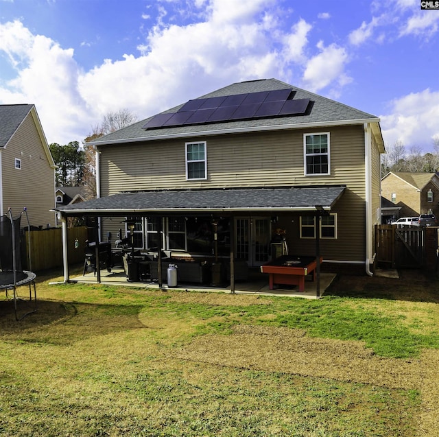 back of property featuring solar panels, a hot tub, a trampoline, a lawn, and a patio