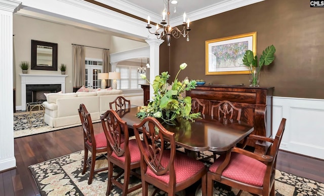 dining space with an inviting chandelier, hardwood / wood-style flooring, ornamental molding, and decorative columns