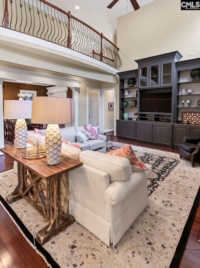 living room with a high ceiling, ceiling fan with notable chandelier, and hardwood / wood-style floors