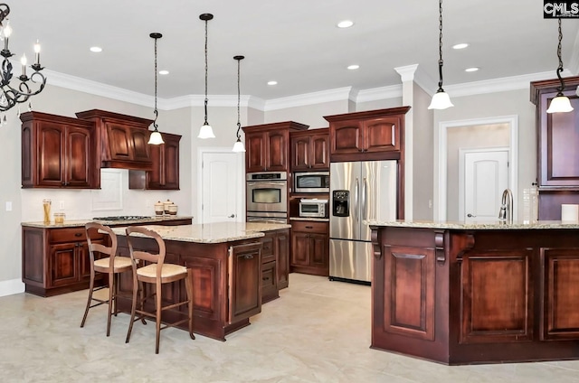 kitchen featuring a breakfast bar, decorative light fixtures, appliances with stainless steel finishes, an island with sink, and light stone countertops