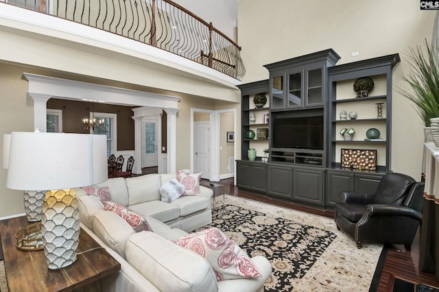 living room with dark hardwood / wood-style flooring, decorative columns, and a chandelier