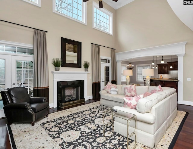 living room with french doors, dark wood-type flooring, sink, a towering ceiling, and ceiling fan with notable chandelier