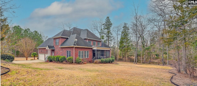 view of side of property featuring a garage, a sunroom, and a lawn