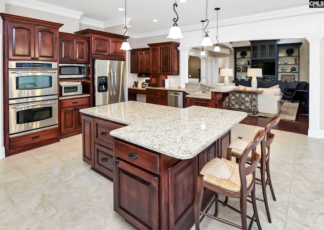 kitchen featuring stainless steel appliances, hanging light fixtures, a breakfast bar, and a spacious island