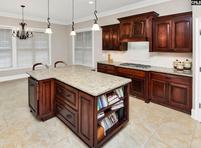 kitchen featuring hanging light fixtures, light stone countertops, stainless steel gas stovetop, and a kitchen island