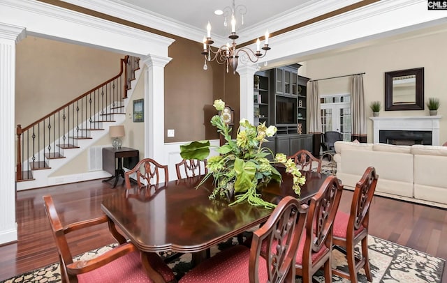 dining room featuring ornamental molding, wood-type flooring, decorative columns, and a chandelier