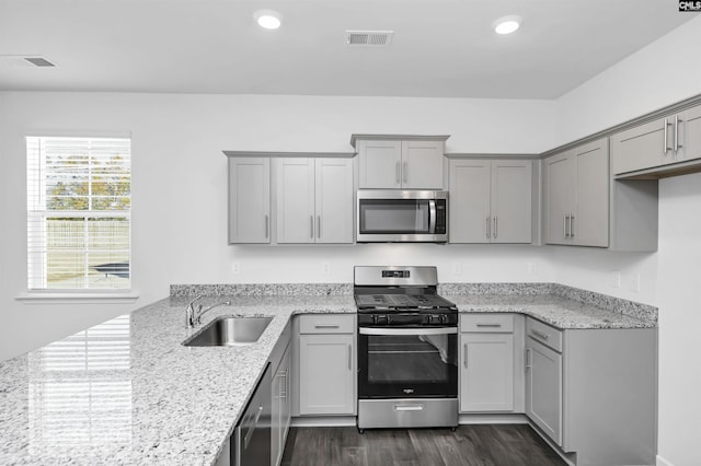 kitchen with dark wood-type flooring, sink, appliances with stainless steel finishes, gray cabinets, and light stone countertops